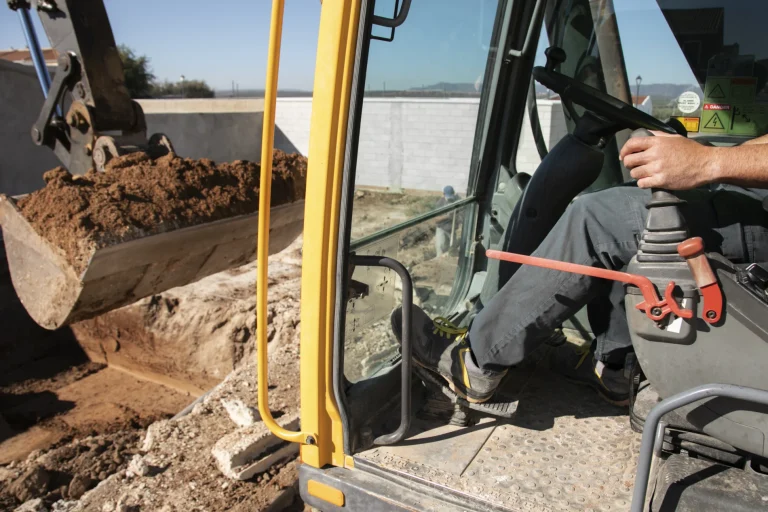 Conducteur de pelle mécanique creusant une fouille lors de travaux de terrassement avant construction